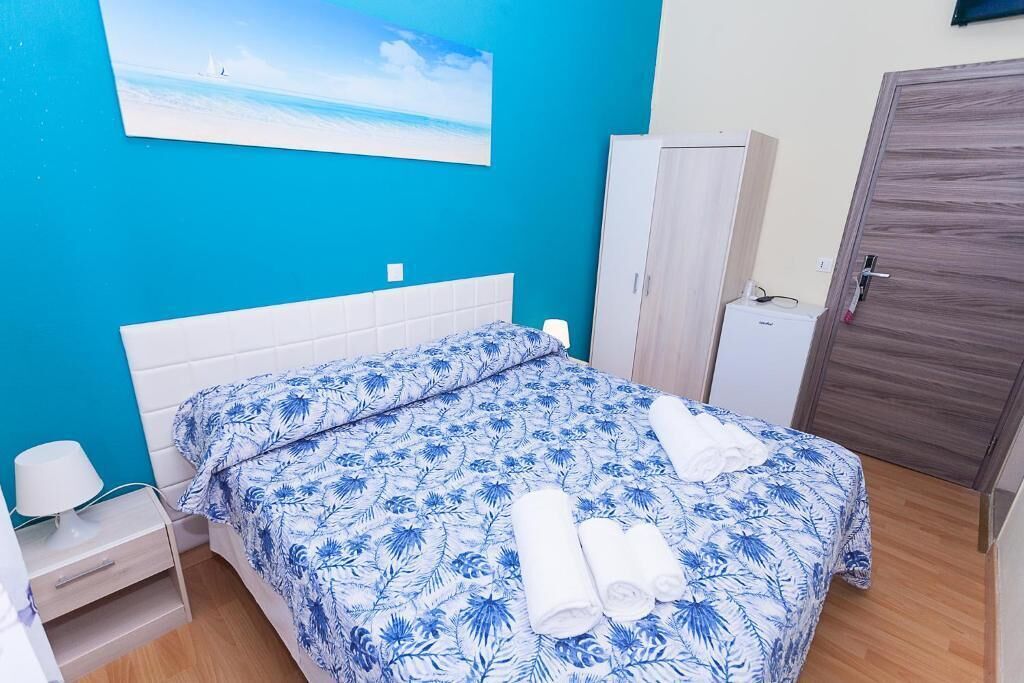 A bedroom with a bed, a nightstand, a wardrobe, and a door.