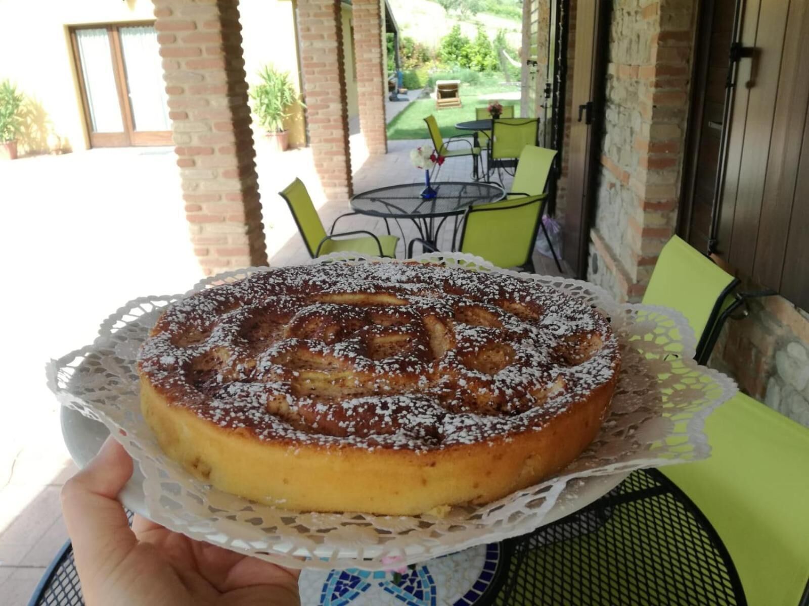 Un pastel redondo sobre un prendedor de encaje, sostenido por una persona.