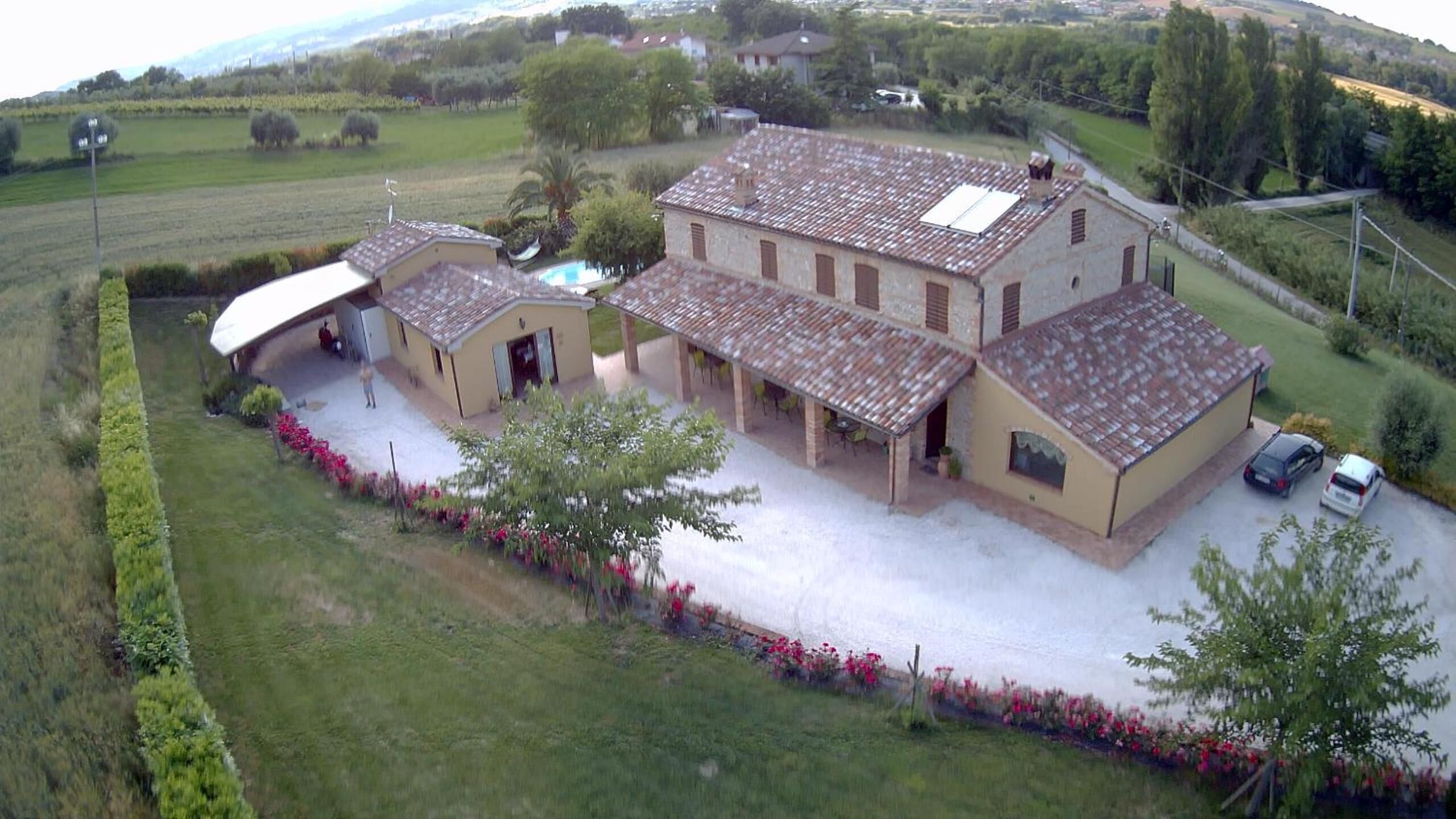 A large, two-story building with a tiled roof, a swimming pool, and a covered patio area.