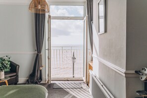 A room with a view of the sea, a wicker lamp, a chair, a small table with a plant, and a radiator. - Hotel Elizabeth (Sidmouth)