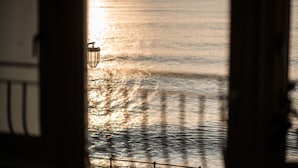 Une vue sur la mer, prise depuis un bâtiment doté d’une balustrade et d’un lampadaire.