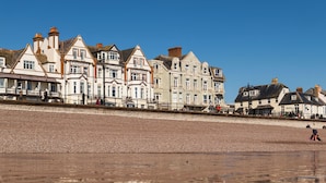 Une rangée de bâtiments historiques, avec une plage de galets au premier plan.