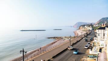 A coastal road with a beach on one side and buildings on the other.