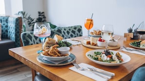 Une table à manger avec différents plats, notamment une salade, du pain et une boisson servie avec une paille.
