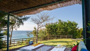 A covered outdoor seating area with a view of the ocean, a wooden deck, and a thatched roof. - Villa Meliti (Corfu)