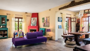 A cozy living room with a purple sofa, a fireplace, and artwork on the walls. - Villa Meliti (Corfu)