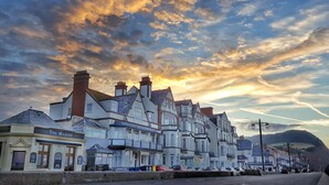 A row of traditional white buildings with multiple chimneys, a sign for 'The Marine' restaurant, and a clear view of the sea in the background.