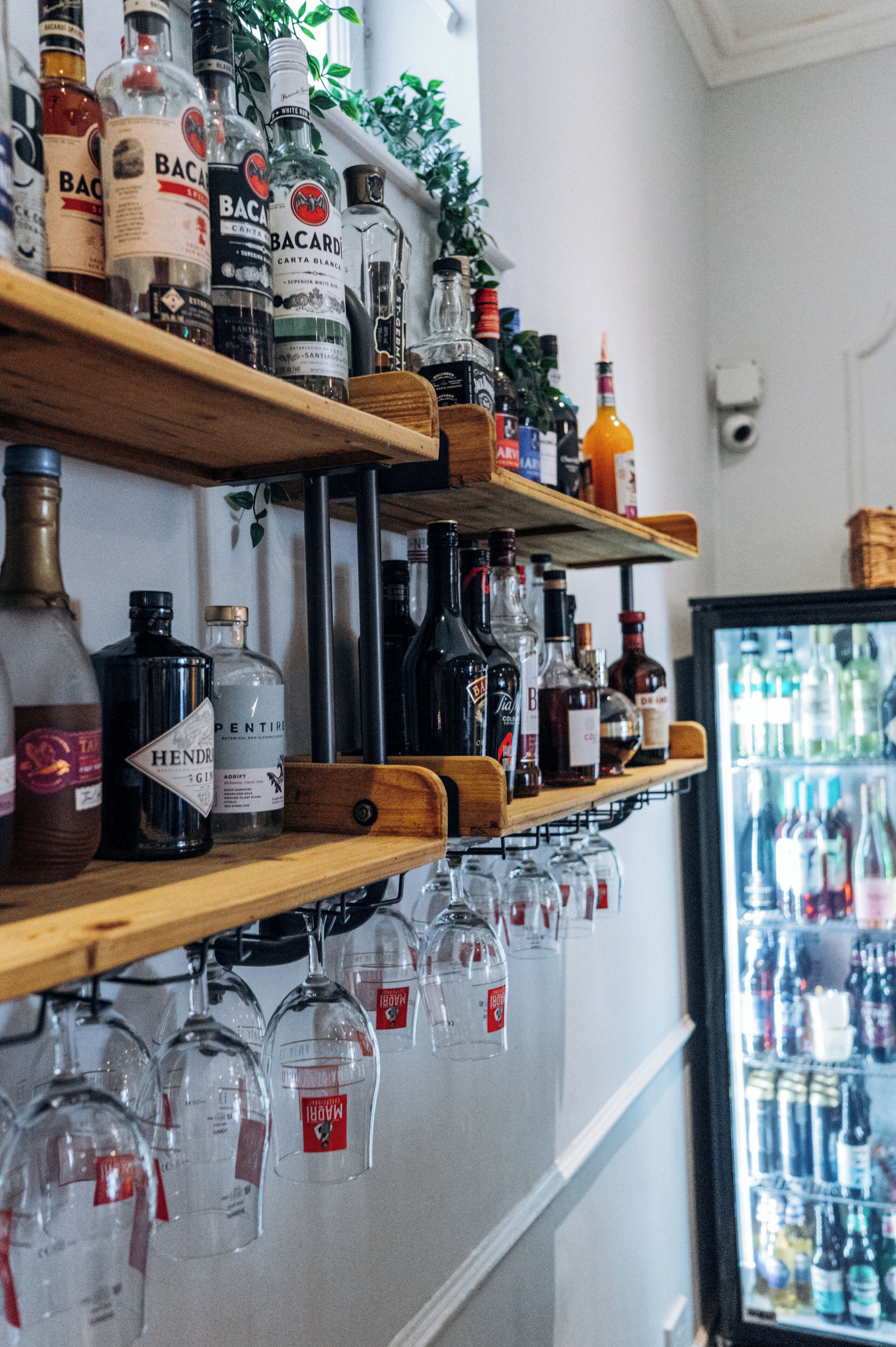 Zona de bar con estantes llenos de botellas de licores y copas de vino.
