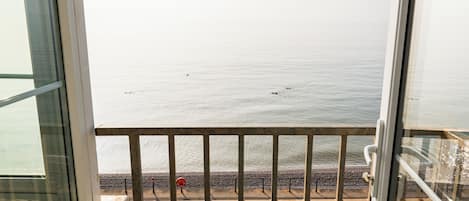 A view from a balcony overlooking a calm sea with a rocky shoreline.