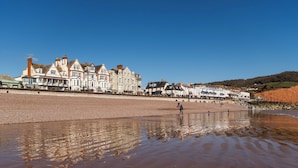 A beachfront hotel with multiple buildings, a sandy beach, and a rocky shoreline.