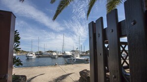 Un puerto deportivo con varias embarcaciones amarradas, una orilla arenosa y una valla de madera.