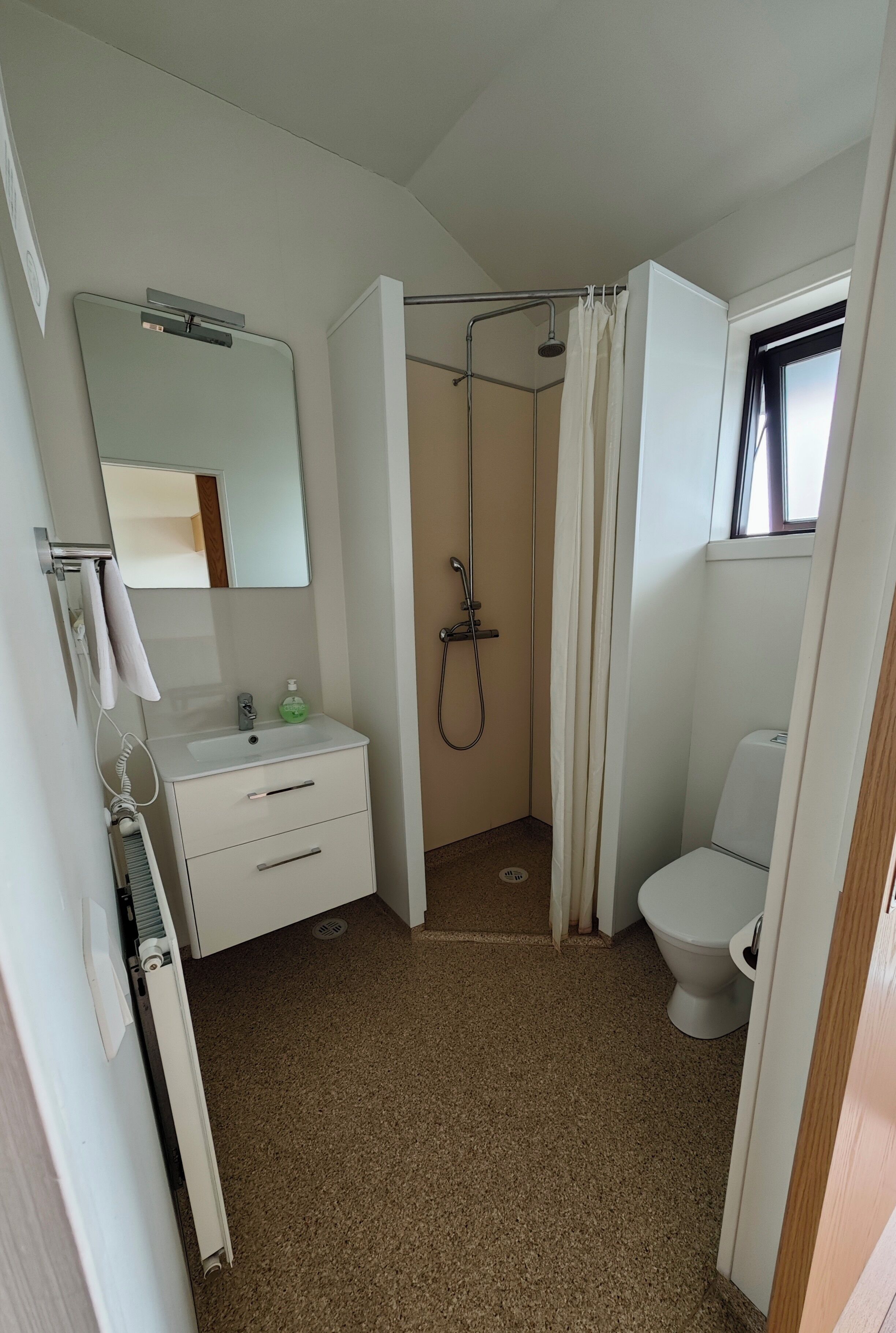 Ein kleines, kompaktes Badezimmer mit Dusche, Toilette und Waschbecken.