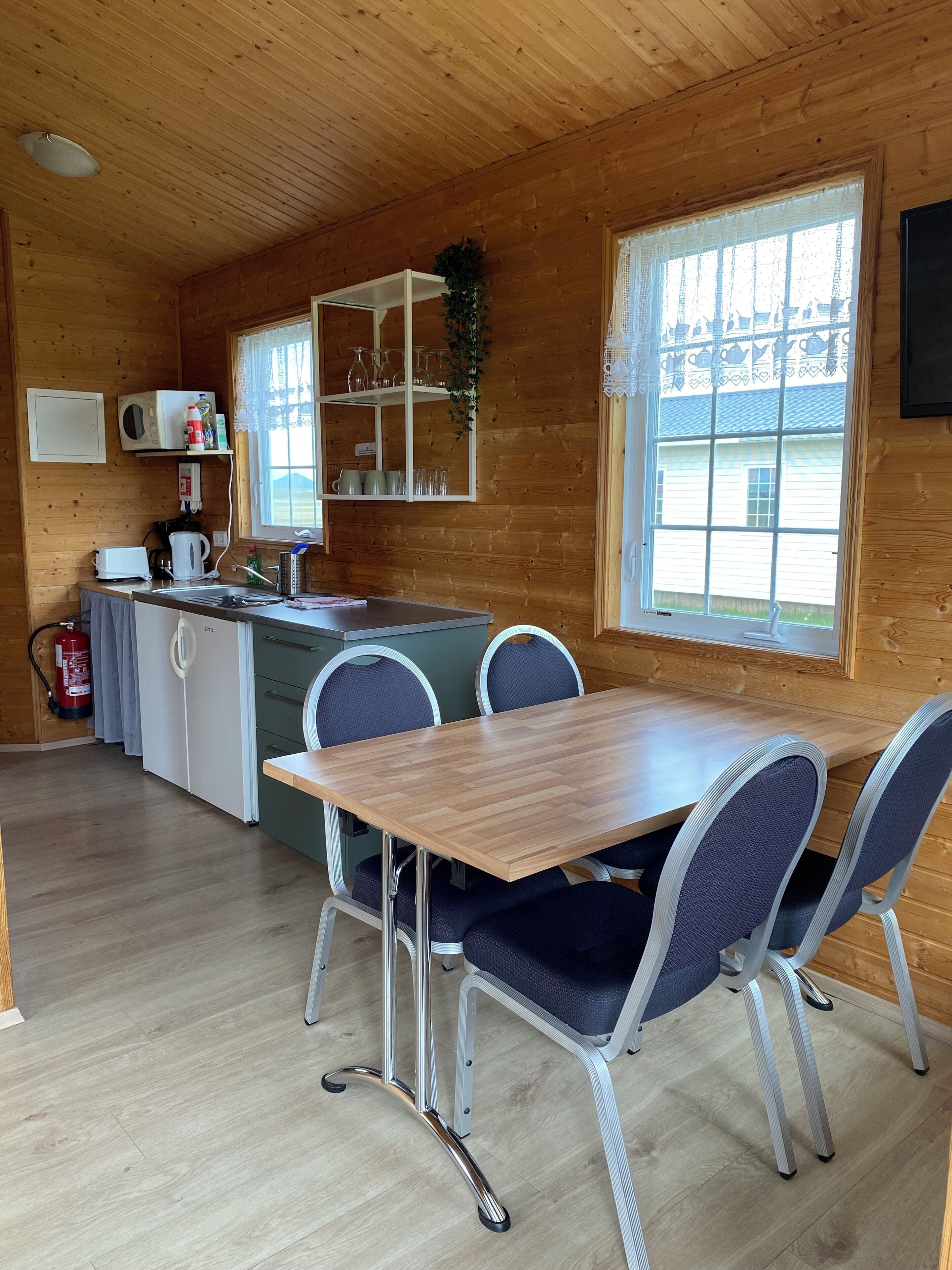 Une cabane en bois dotée d’un coin cuisine comprenant une table en bois, des chaises et un four à micro-ondes.