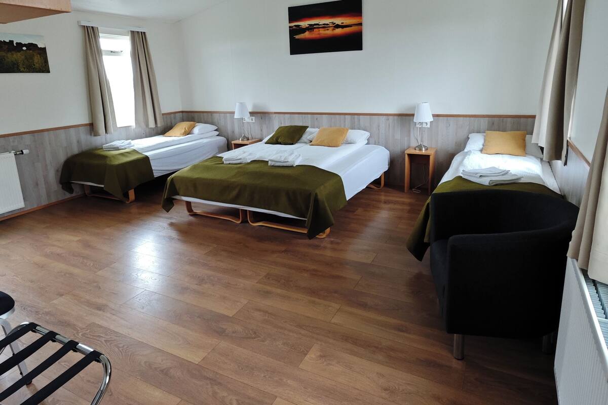 Een hotelkamer met twee eenpersoonsbedden, een tafeltje, een stoel en uitzicht op de zonsondergang.