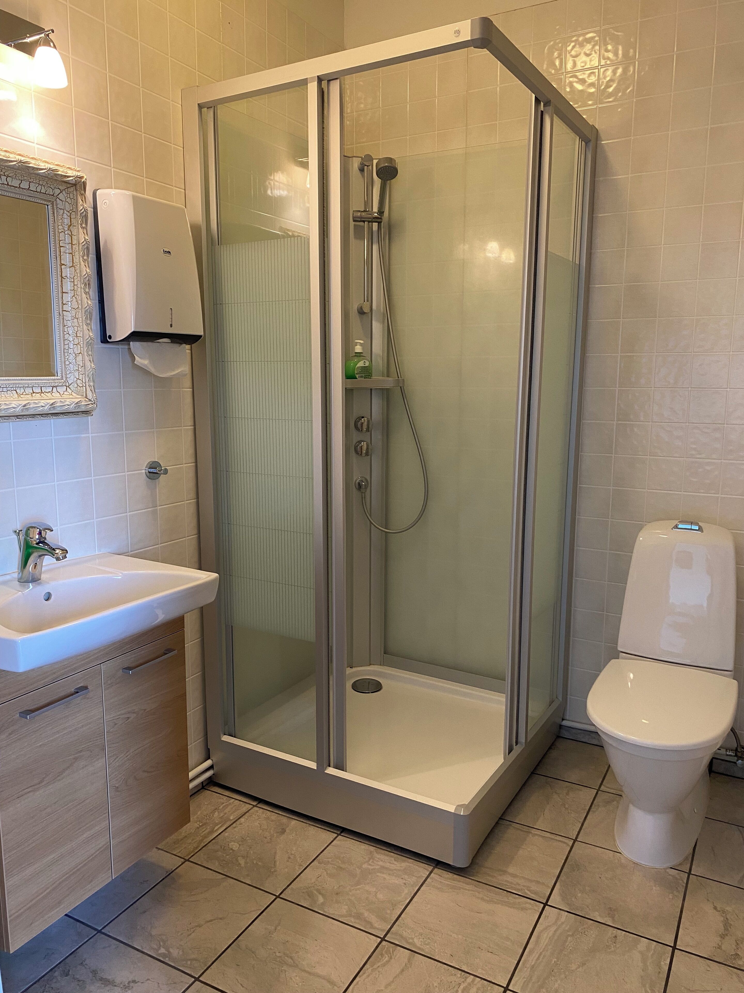 Un baño moderno con ducha de vidrio, inodoro y lavamanos con espejo.