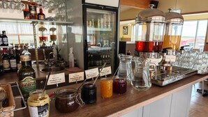 A bar area with various bottles, jars of condiments, and a coffee machine.