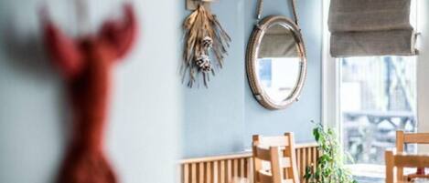 A room with a round mirror, a wooden chair, and a table.
