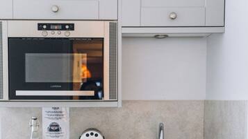 A kitchen with a built-in oven, a coffee maker, a sink, and a countertop with various items.