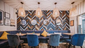 Un restaurante con pared de diseño encalle, espejos redondos y asientos tapizados en azul.