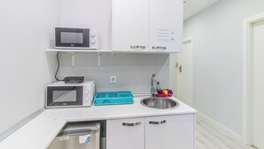 Une petite cuisine équipée d’un four à micro-ondes, d’un grille-pain, d’un évier et de placards de rangement.