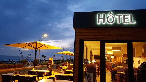 Un hotel con mesas al aire libre y vistas al océano.