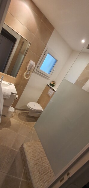 A modern bathroom with a toilet, sink, and a handheld showerhead. - Hôtel Côte d'Argent (Lacanau)
