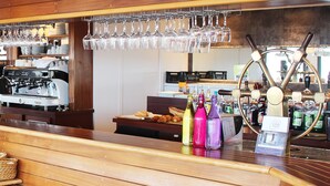 Zona de bar con una máquina de café, botellas de bebidas y una estantería para vinos.