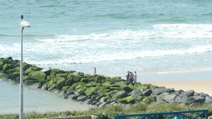 Una playa con un rompeolas rocoso, una orilla arenosa y un cartel.