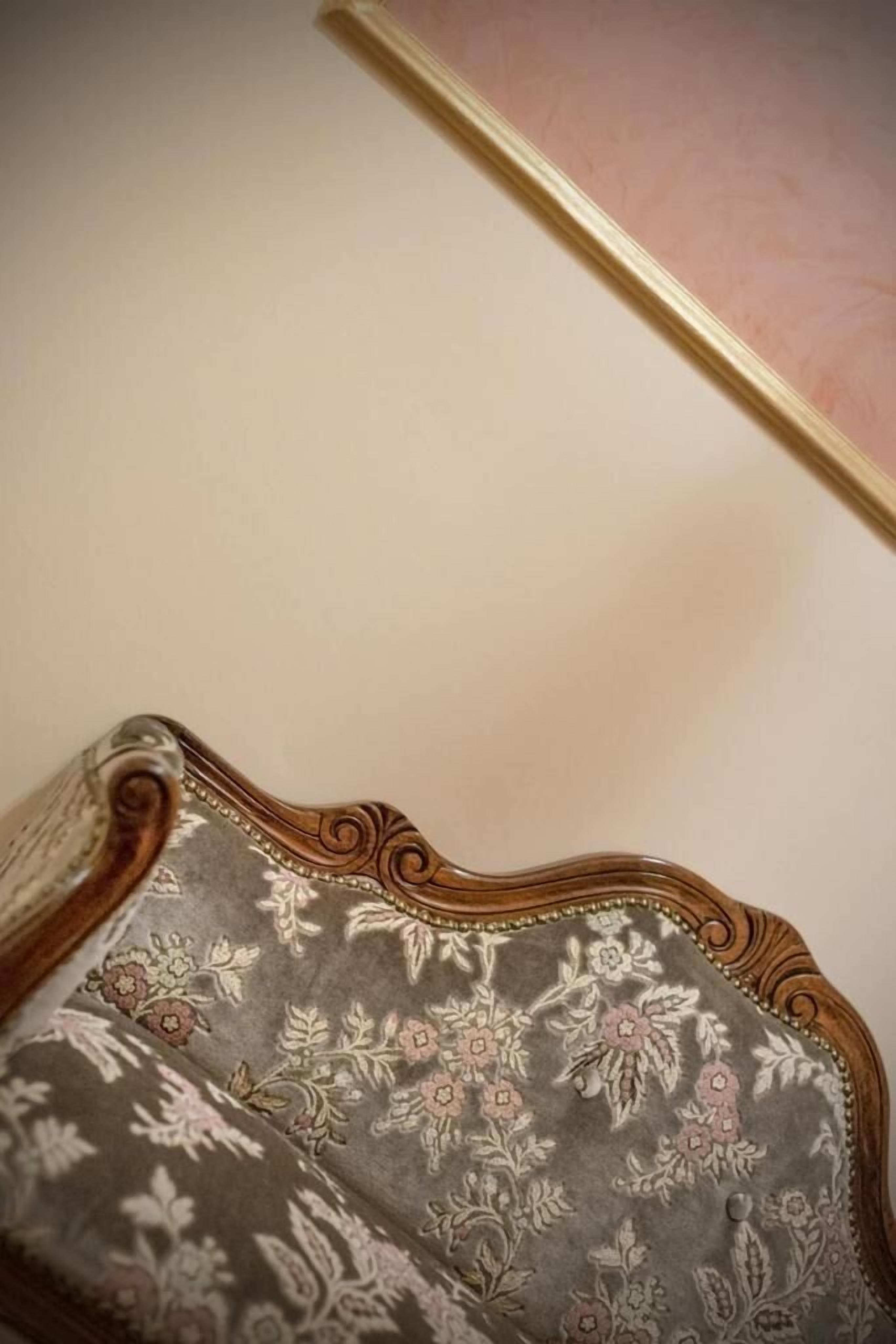 Een stoel met een bloemmotief en een houten frame.