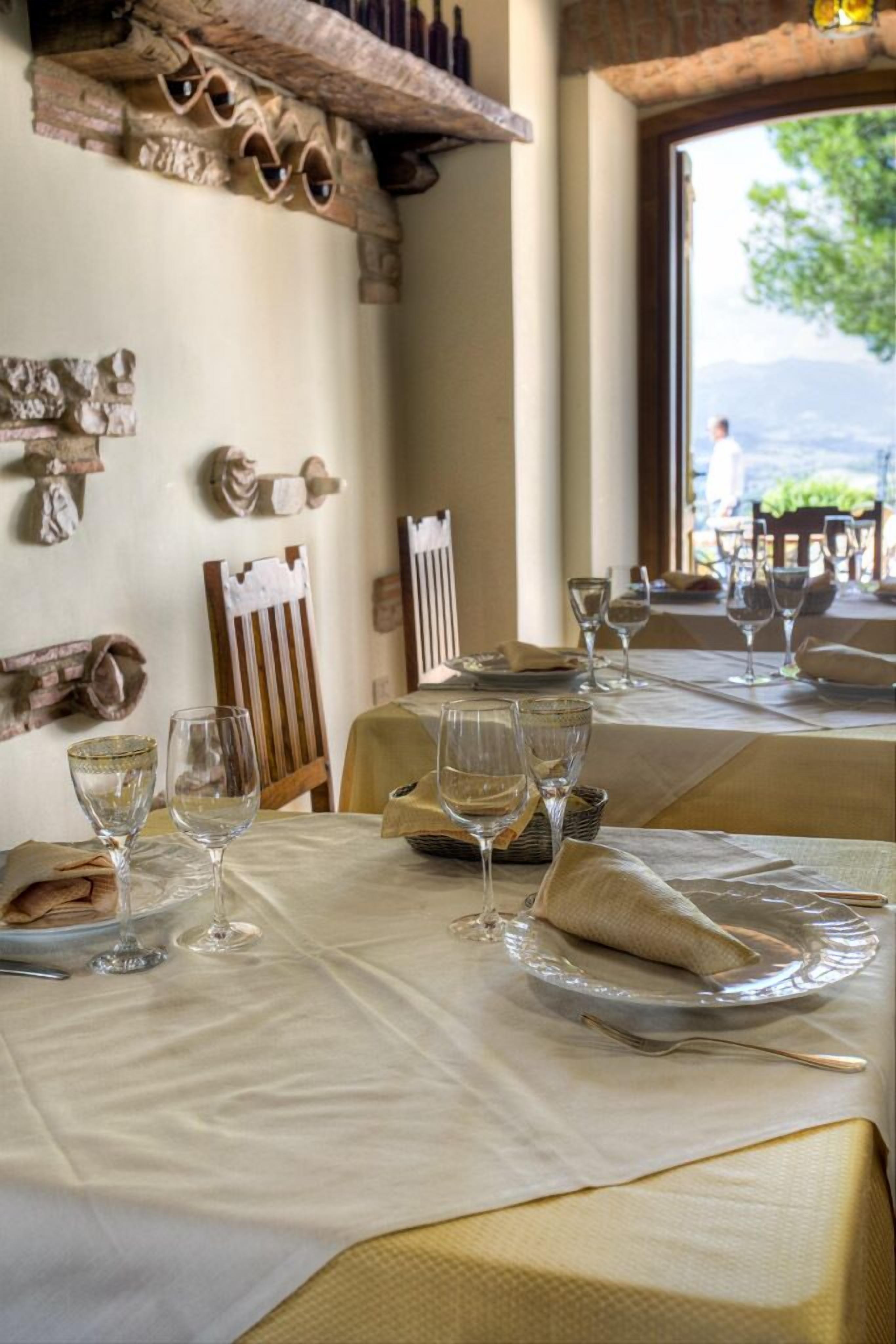 Un espace repas avec des tables mises pour le repas, où l’on trouve de la vaisselle et des verres en verre transparent.