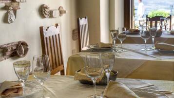 Un espace repas avec des tables mises pour le repas, où l’on trouve de la vaisselle et des verres en verre transparent.