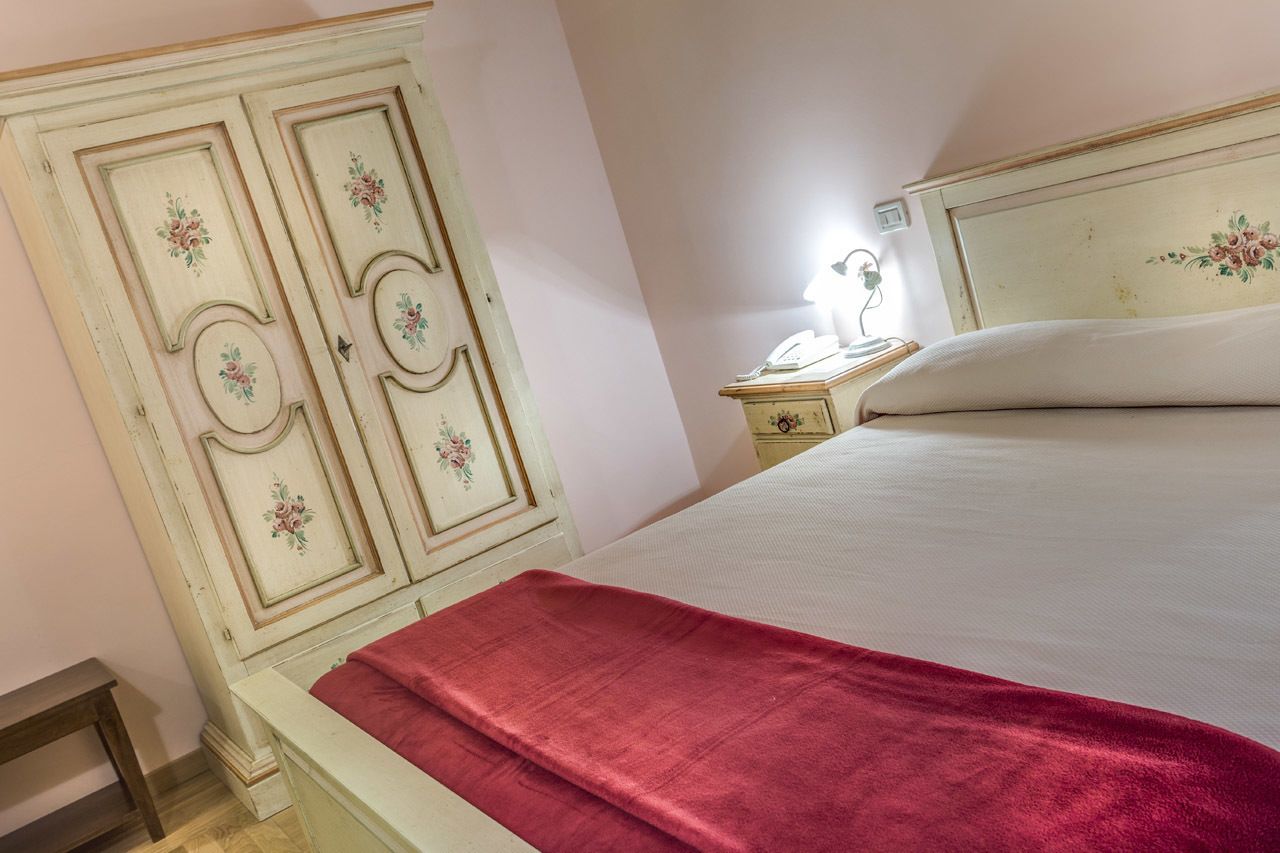 A bedroom with a bed, a nightstand, a dresser, and a red throw blanket.