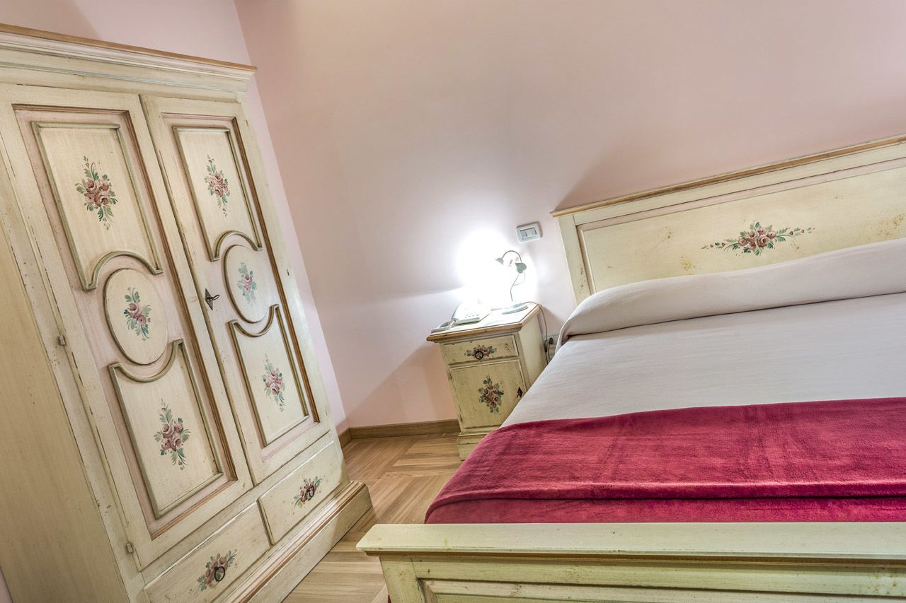 A bedroom with a bed, a nightstand, and a wardrobe.
