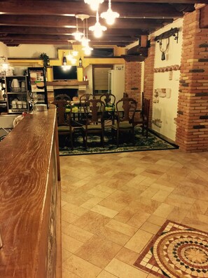 A dining area with a wooden table and chairs, a patterned rug, and a brick wall. - La Castellaia Resort (Fabriano)