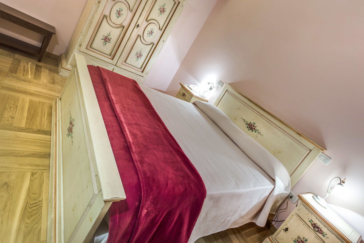 Un dormitorio con cama, mesita de noche, cómoda y espejo.