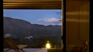 Una terraza de madera con una silla de descanso, una mesa con una vela y vistas a montañas.