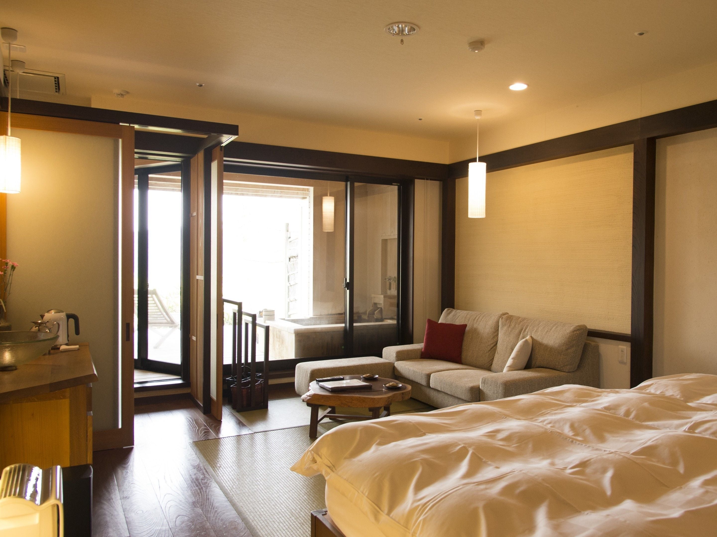Una habitación de hotel con cama, sofá, mesa de centro y escritorio con hervidor.