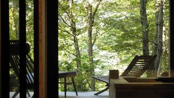 A view from a room with a wooden deck, overlooking a forested area.