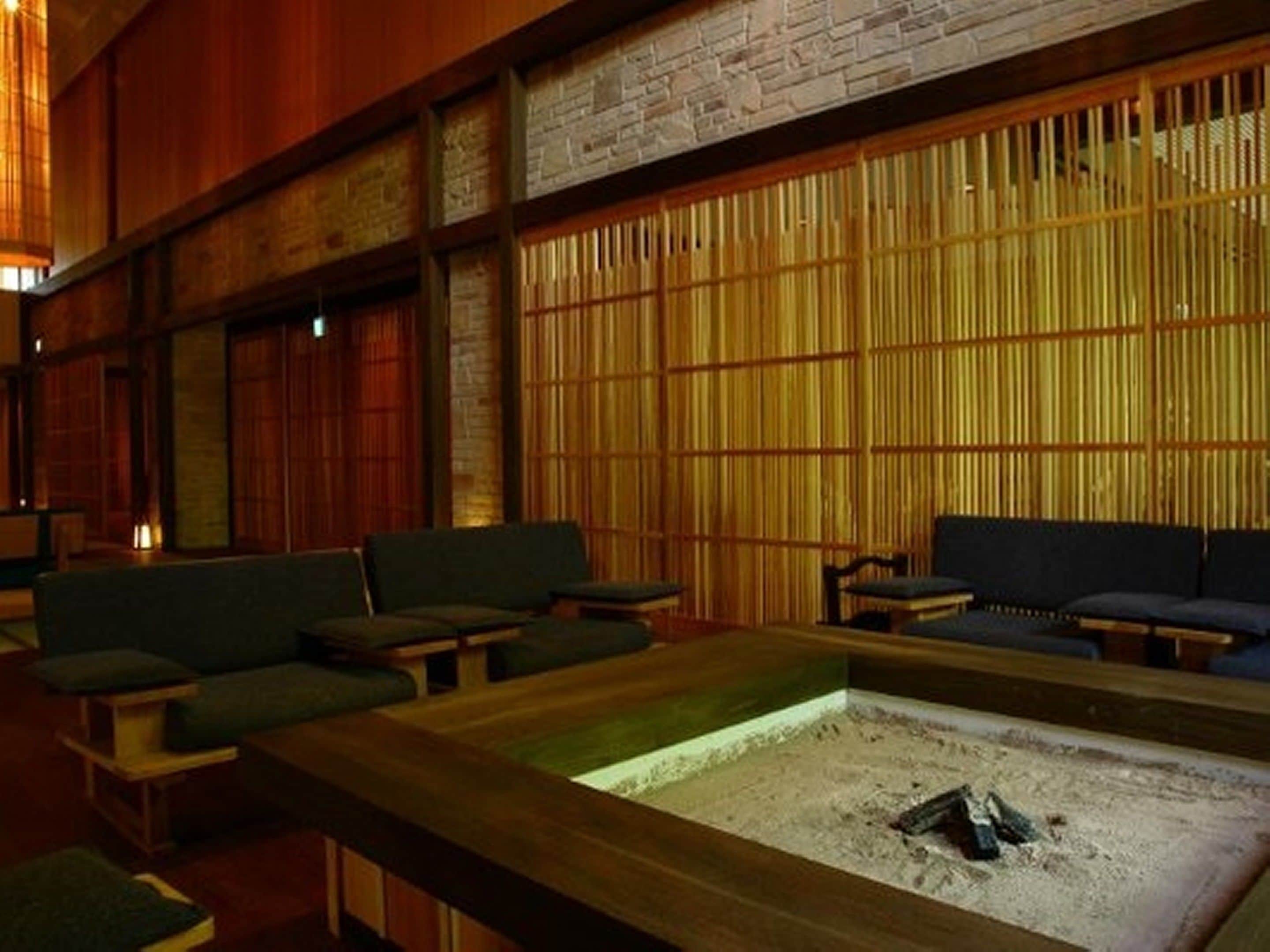 A cozy lounge area with wooden furniture and a central fire pit.
