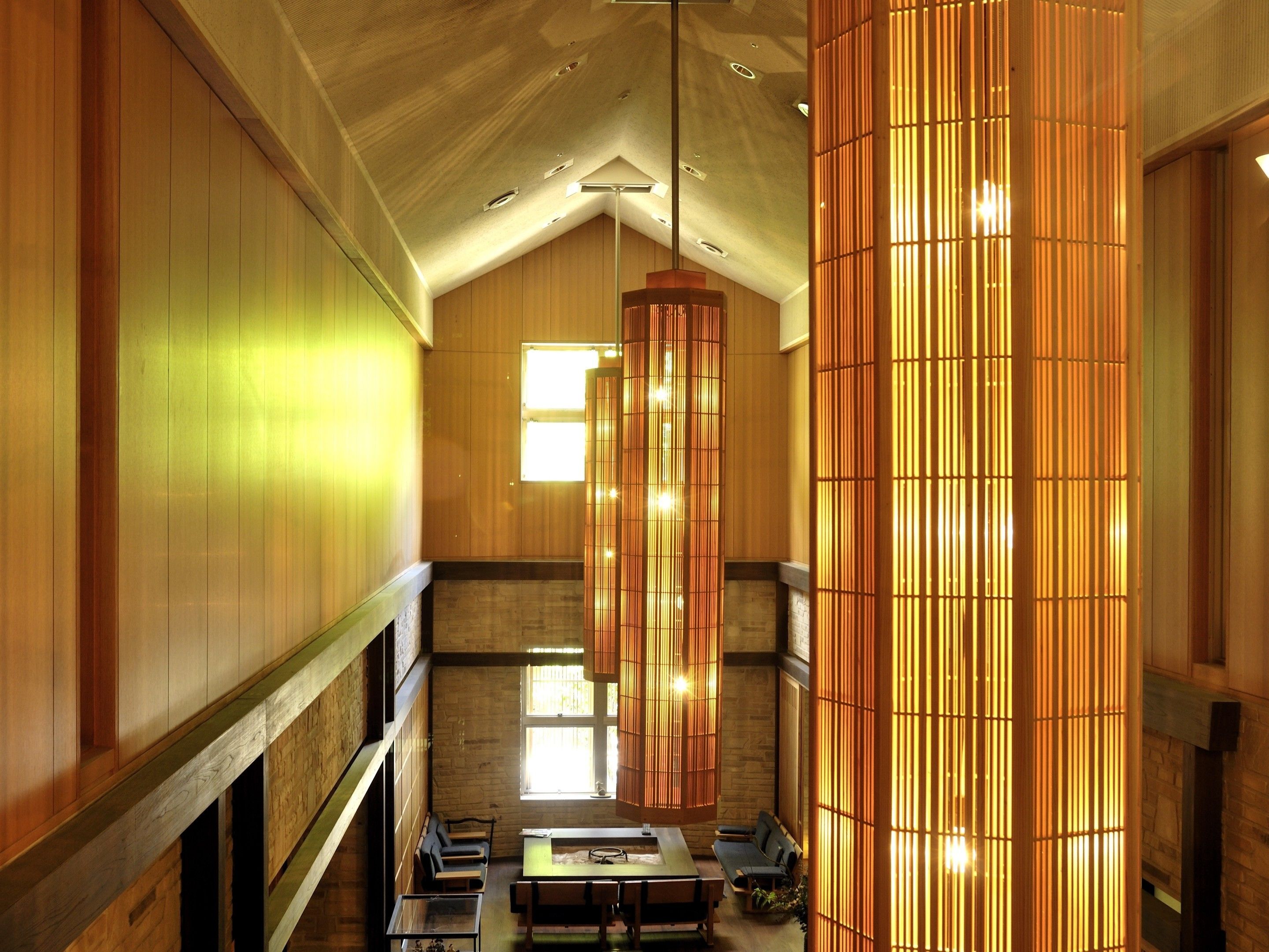 A spacious interior with high ceilings, wooden paneling, and a central seating area with tables and chairs.