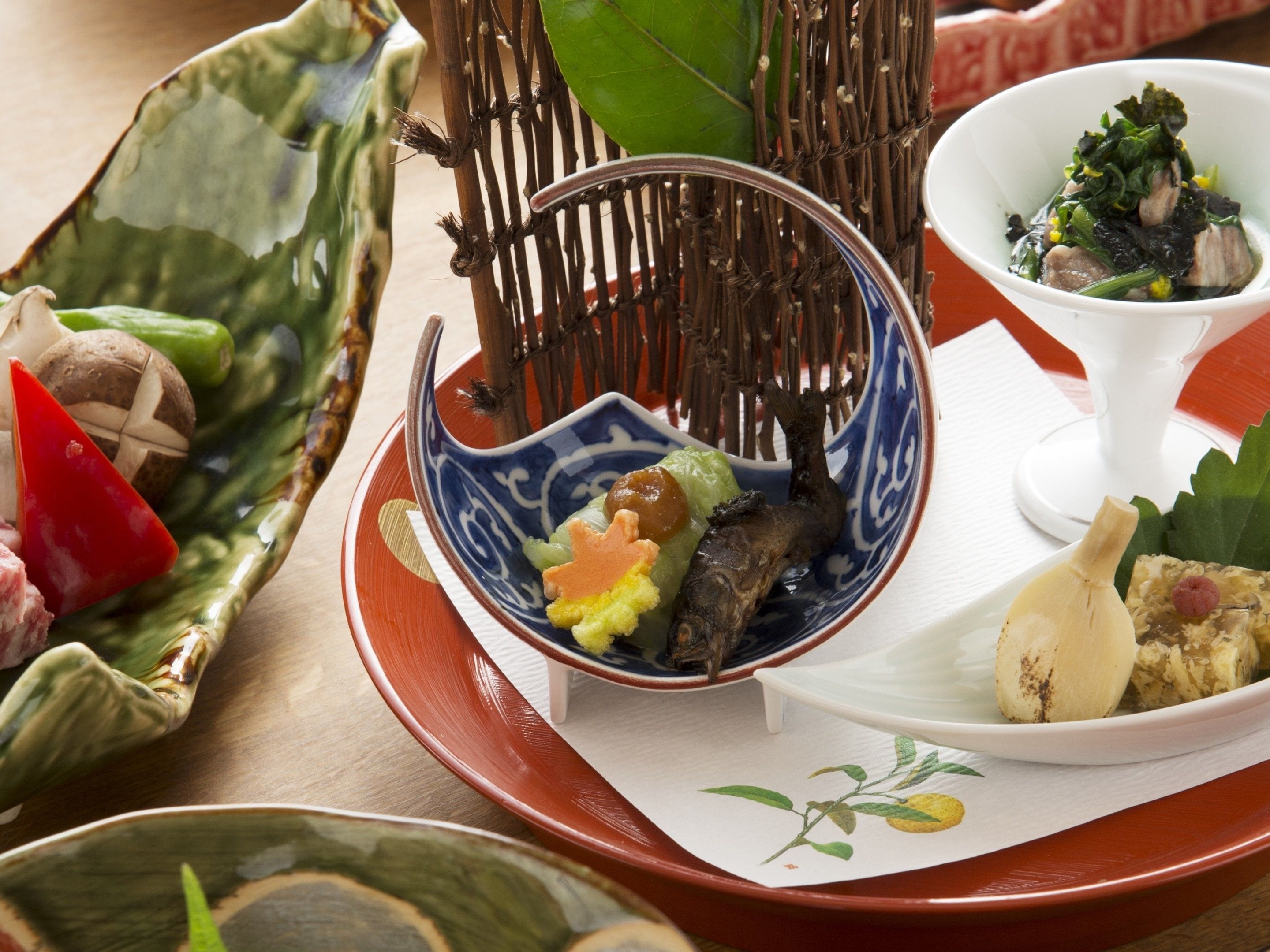 A variety of dishes on a table, including a bowl with vegetables and a small dish with a piece of meat.