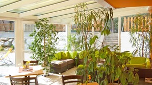 Une terrasse ensoleillée avec une table et des chaises, un canapé et des plantes en pot.