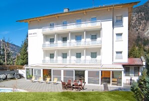 Un hôtel à plusieurs étages doté de balcons, d’une piscine et d’un espace extérieur aménagé pour s’asseoir.