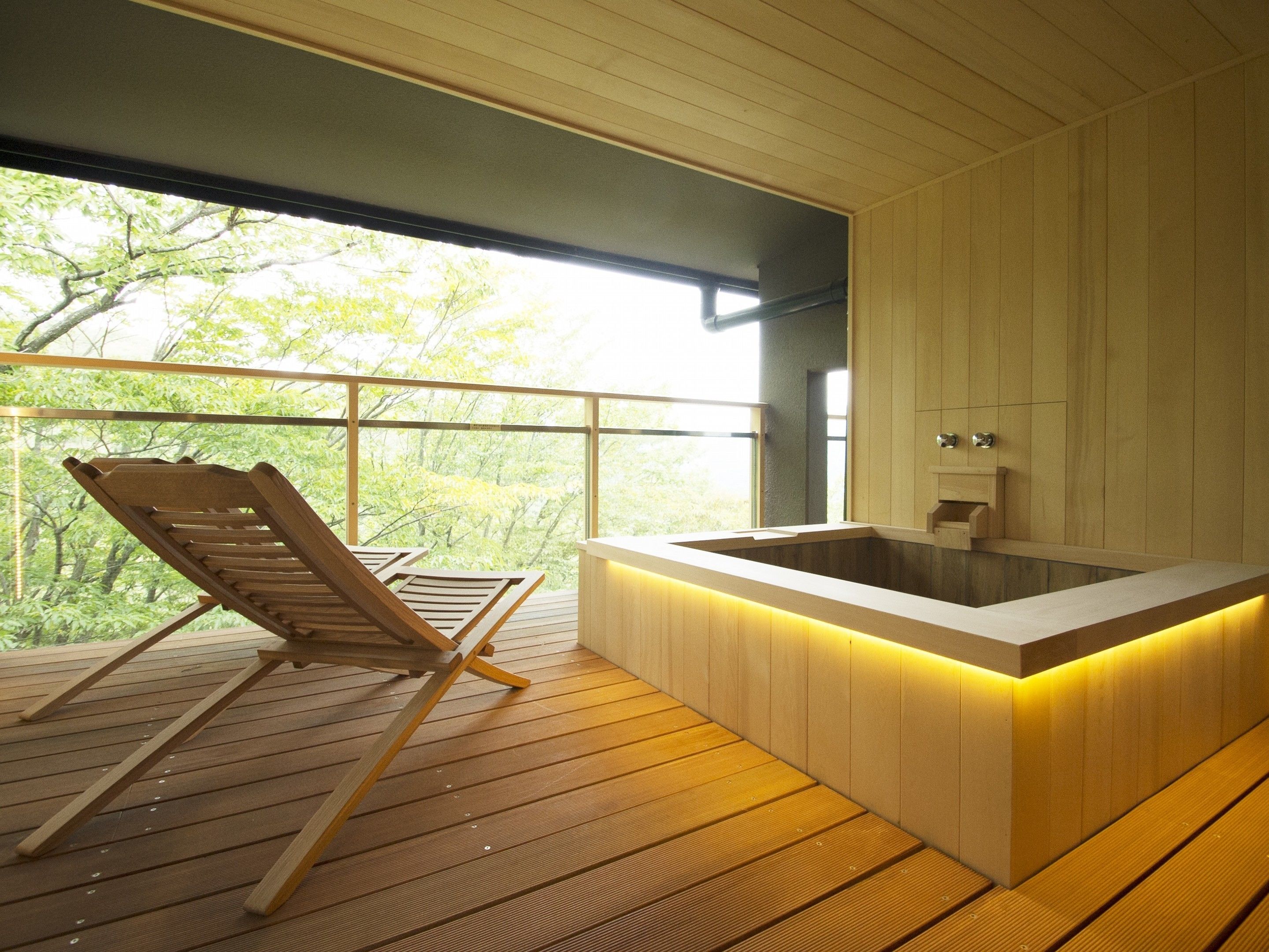 A wooden deck with a wooden chair and a hot tub.