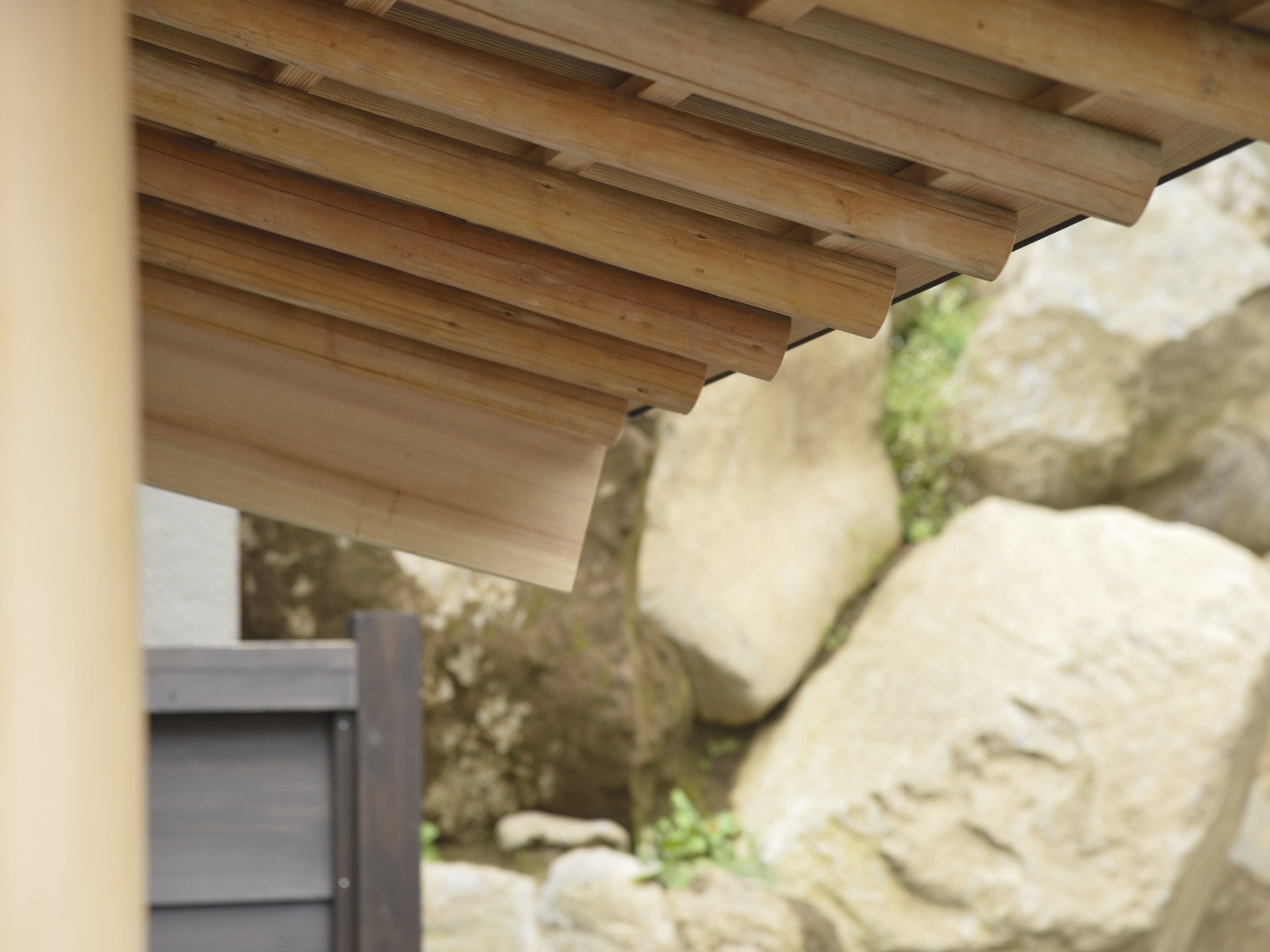A wooden pergola structure with a slatted roof design.