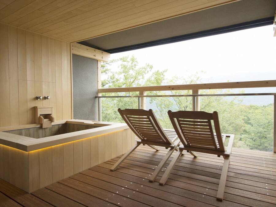 Une terrasse en bois avec deux chaises en bois et un jacuzzi.