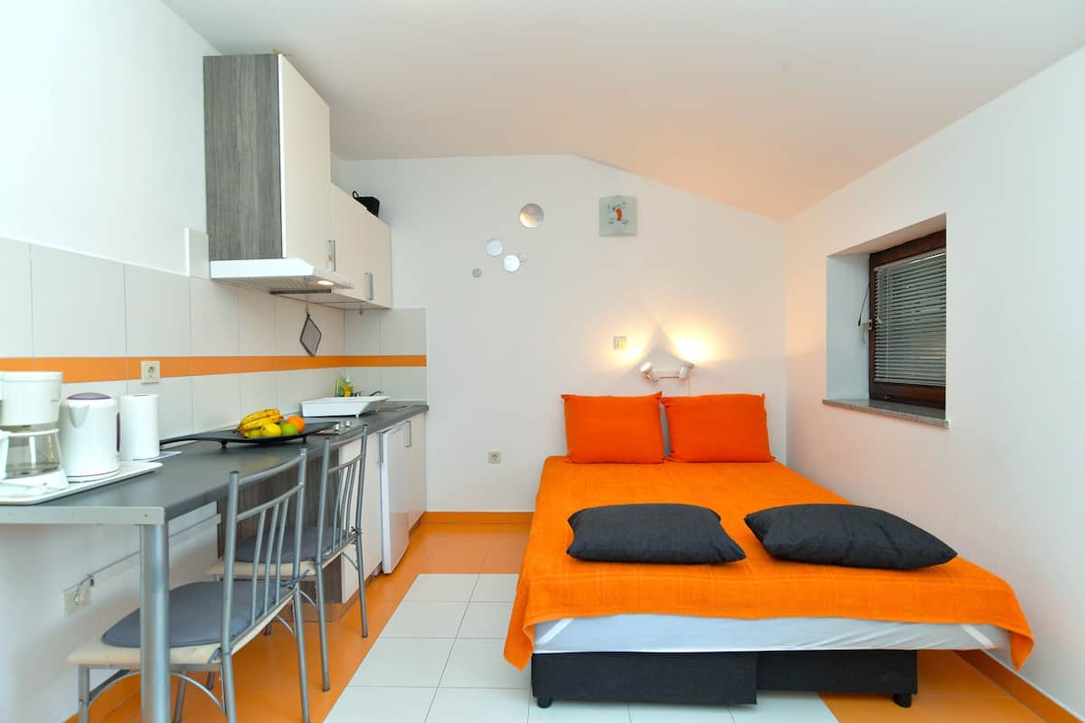 Een kleine slaapkamer met een bed, twee kussens, een bureau en een stoel.