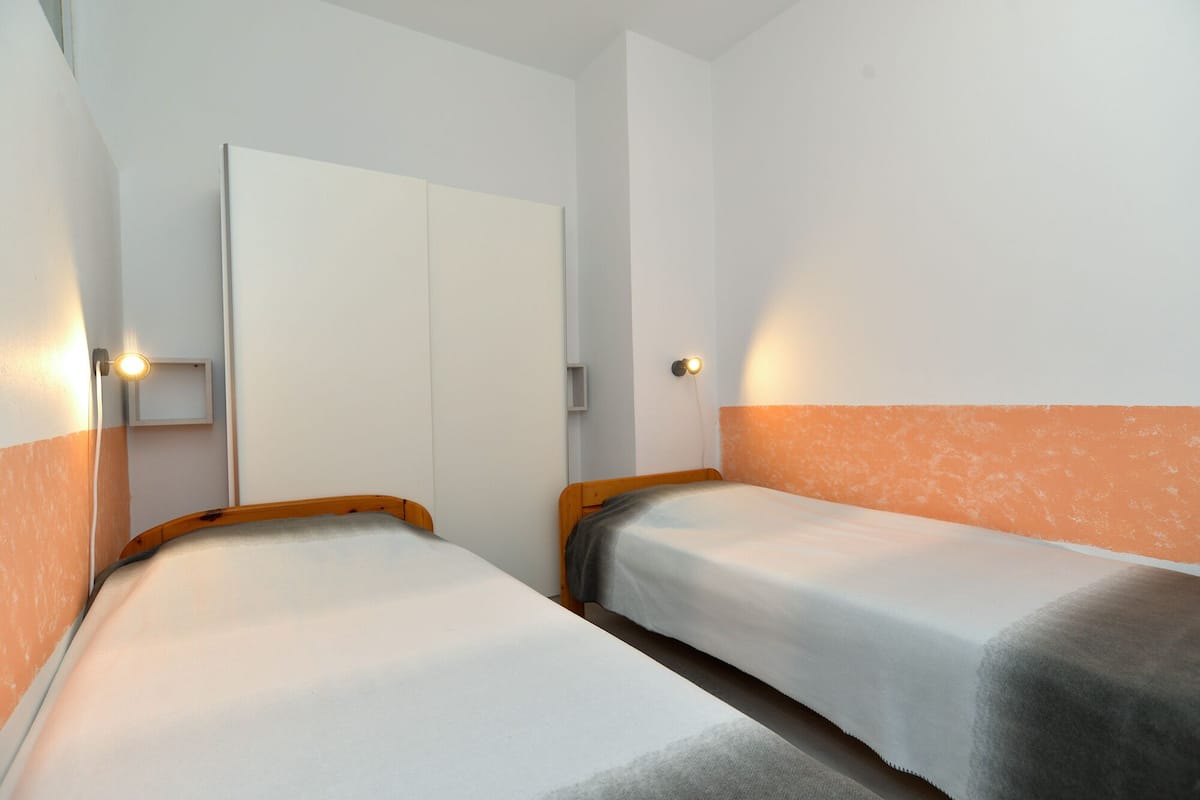 Een kamer met twee enkele bedden, een garderobe en twee wandlampen.
