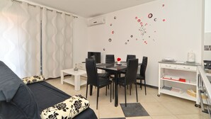 Un salon moderne comprenant un canapé, une table à manger avec des chaises, un meuble blanc et un mur agrémenté d’éléments décoratifs.