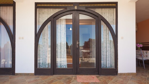 A large, arched door with the number 6 above it, leading to a room with a tiled floor and a small rug in front. - Apartment Milorad 324 (Medulin)